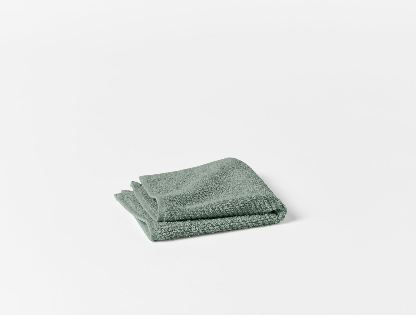 Coyuchi Air Weight wash cloth folded, sage green terry texture visible.
