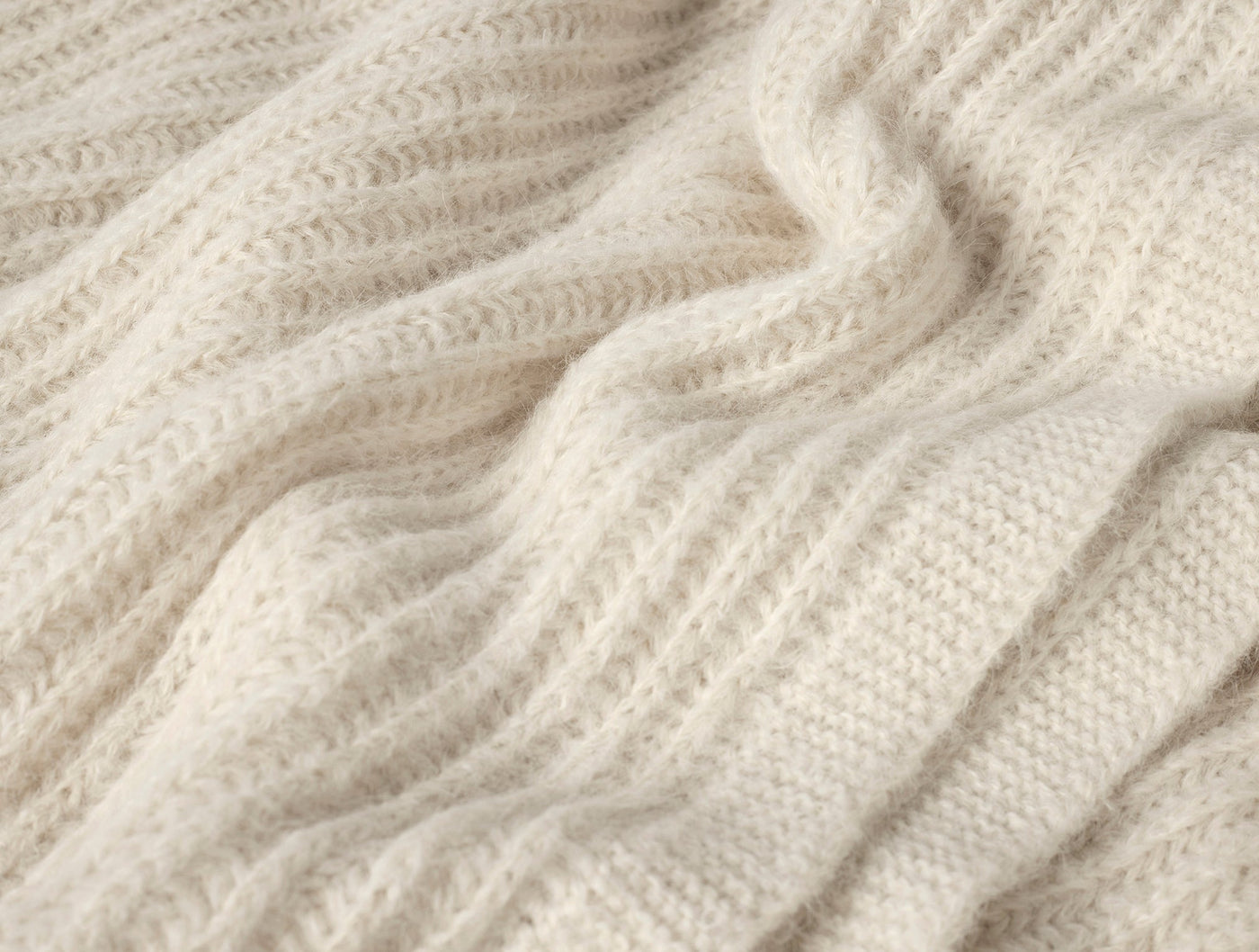 Ivory Suri alpaca knit throw draped to show ribbed texture and soft dimensional weave.