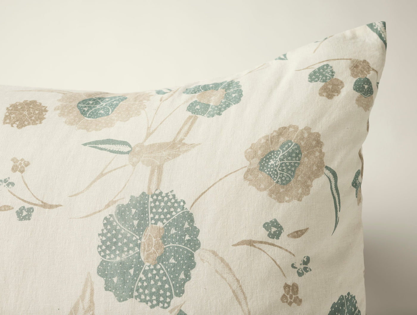 Corner detail of Aurora Print sham, teal and taupe floral motifs on ivory linen.