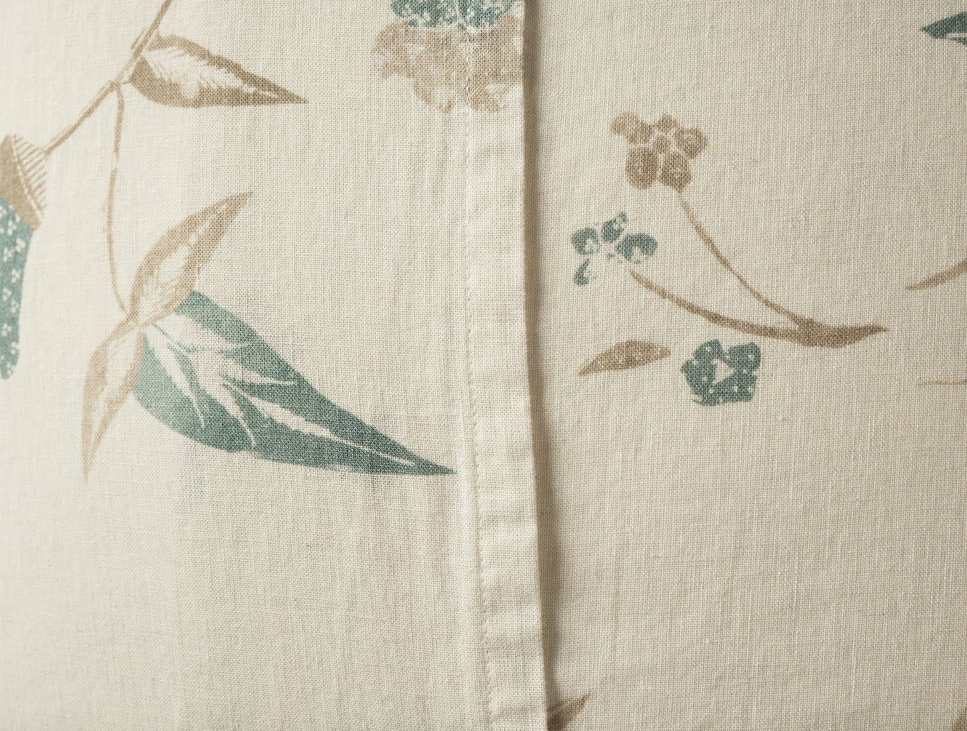 Close-up of Coyuchi Aurora Print sham hem, ivory linen with sage and taupe botanical print.
