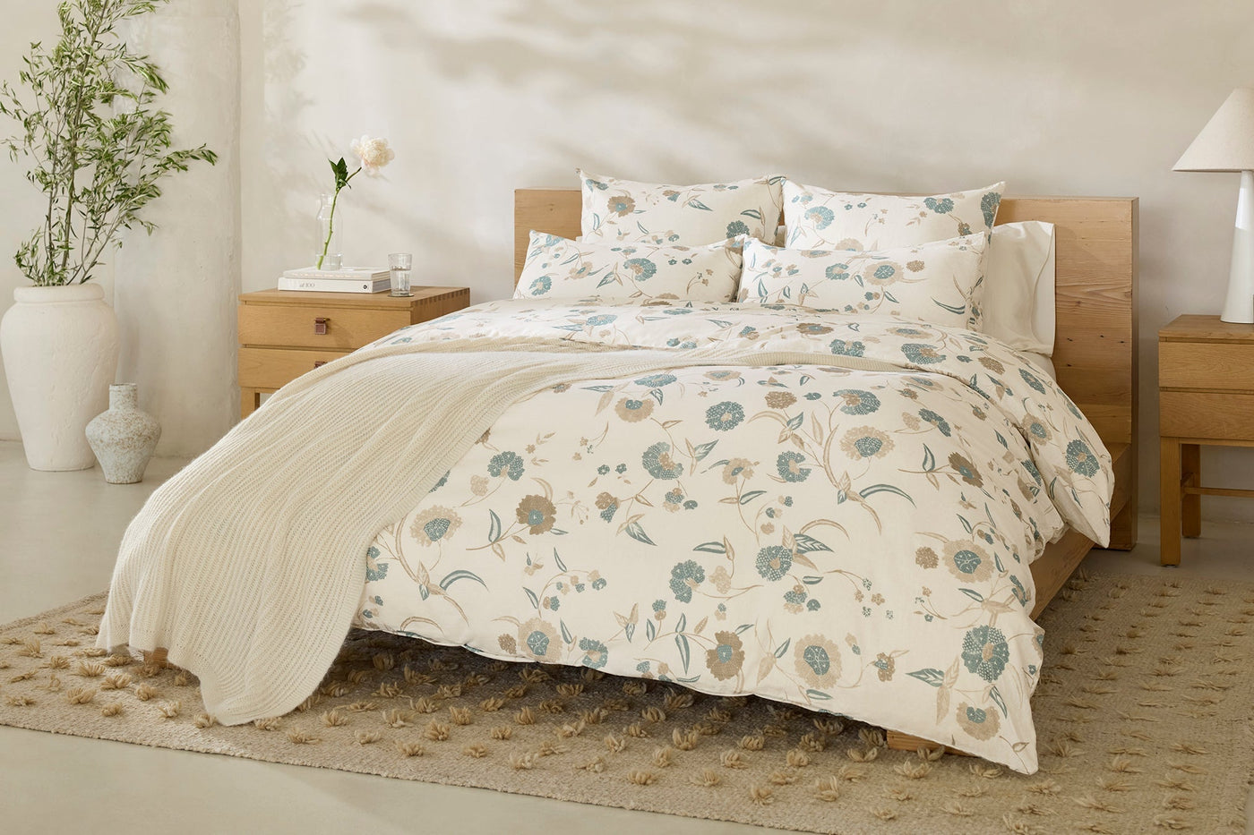 Coyuchi Aurora Print duvet cover in ivory with blue and taupe floral pattern, styled on bed.