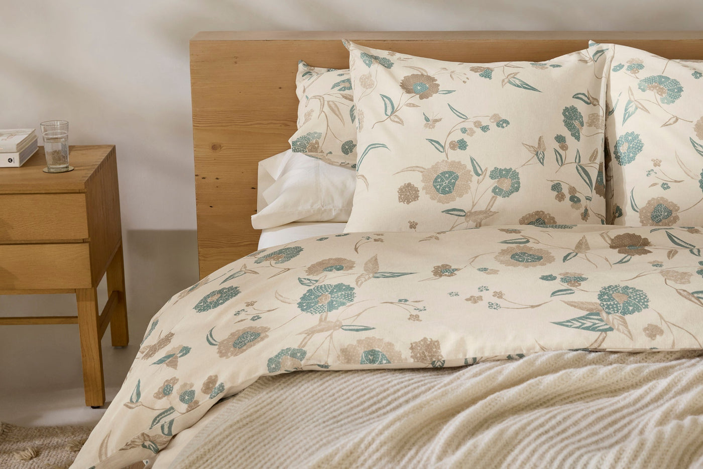 Coyuchi Aurora Print duvet cover styled on bed, ivory with blue and taupe floral pattern.