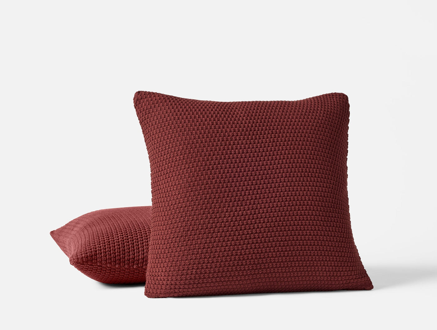 Burgundy chunky knit texture close-up on two stacked Avalon throw pillows.