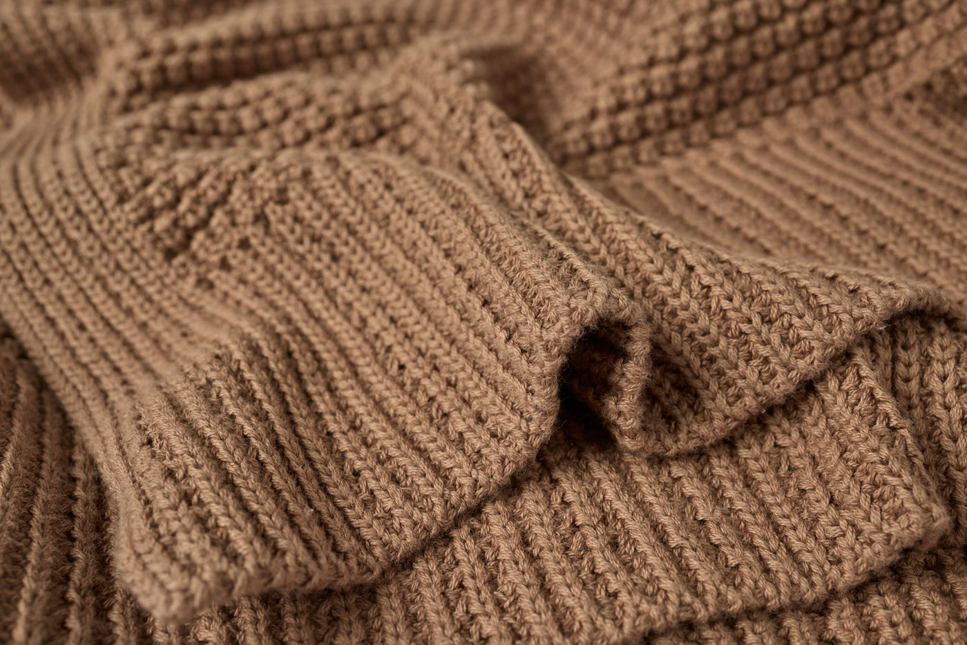 Close-up of Coyuchi Avalon Knit Throw in camel, showing chunky ribbed texture and drape.
