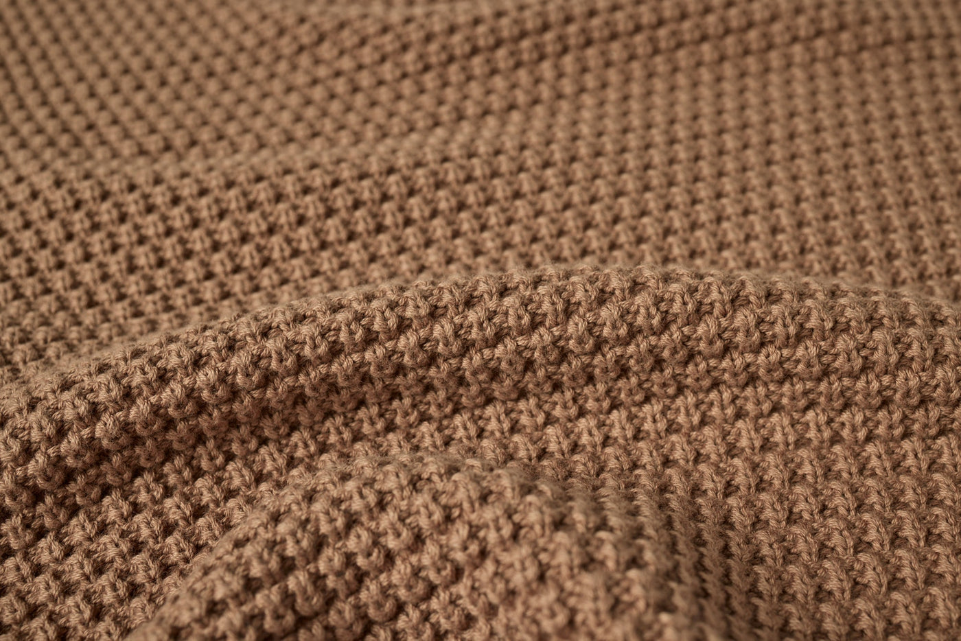 Close-up of Coyuchi Avalon Knit Throw showing toffee waffle-knit texture and soft drape.