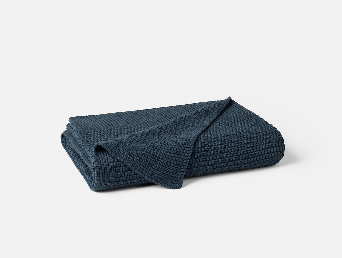 Coyuchi Avalon Knit Throw folded, showing waffle-knit texture in deep navy blue.