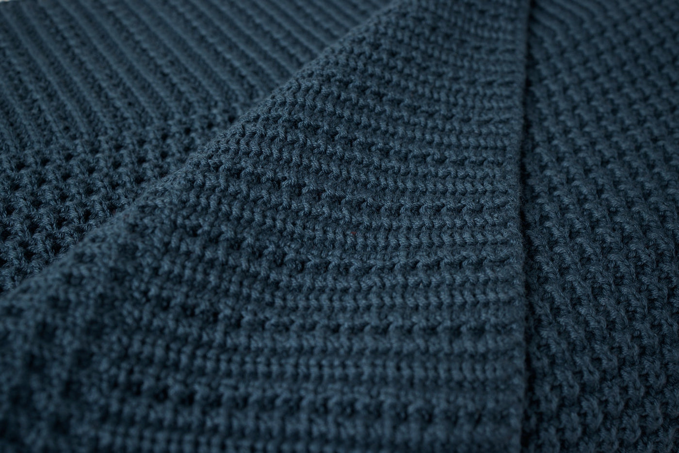 Close-up of Coyuchi Avalon Knit Throw in deep navy, showing waffle-knit texture and folded edge.