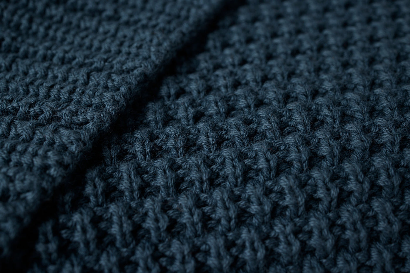 Close-up of Coyuchi Avalon Knit Throw's chunky waffle-knit texture in deep navy.
