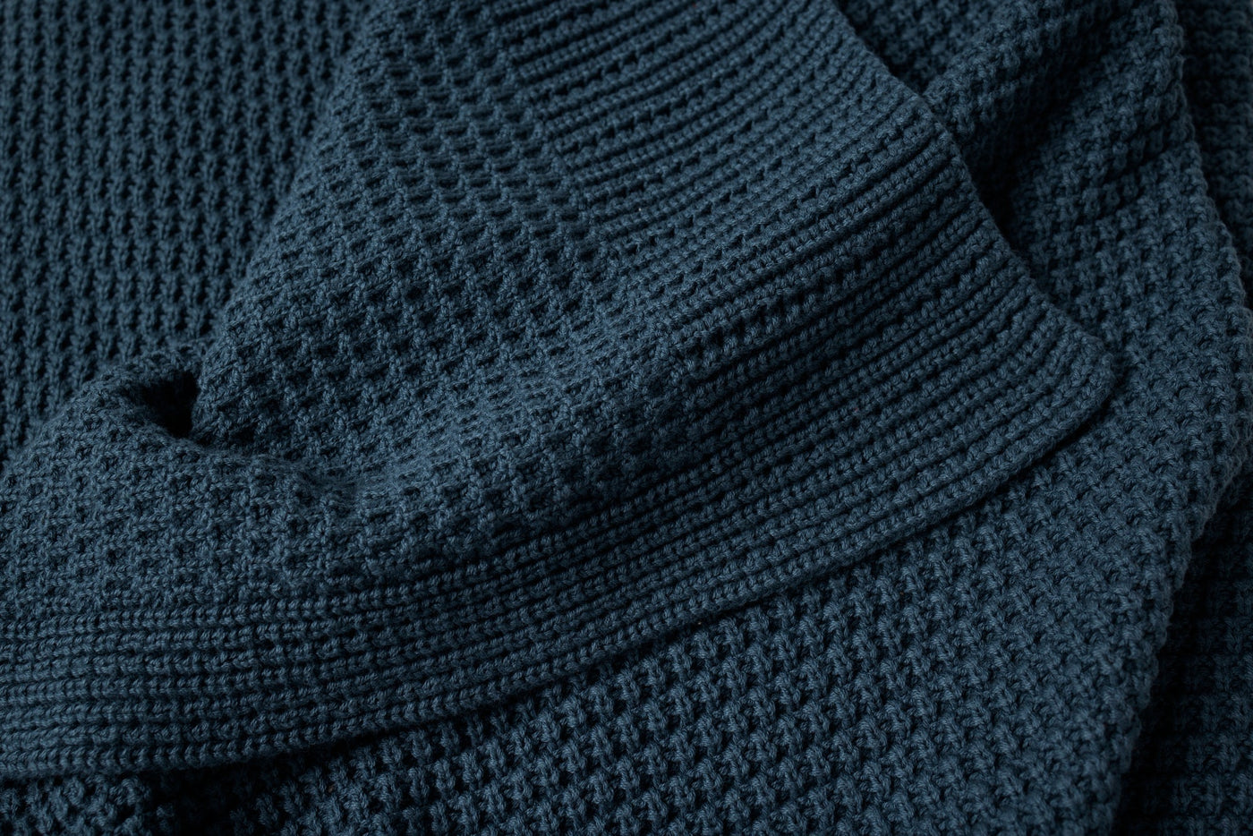 Close-up of Coyuchi Avalon Knit Throw in navy, showing waffle-knit texture and folded edge.
