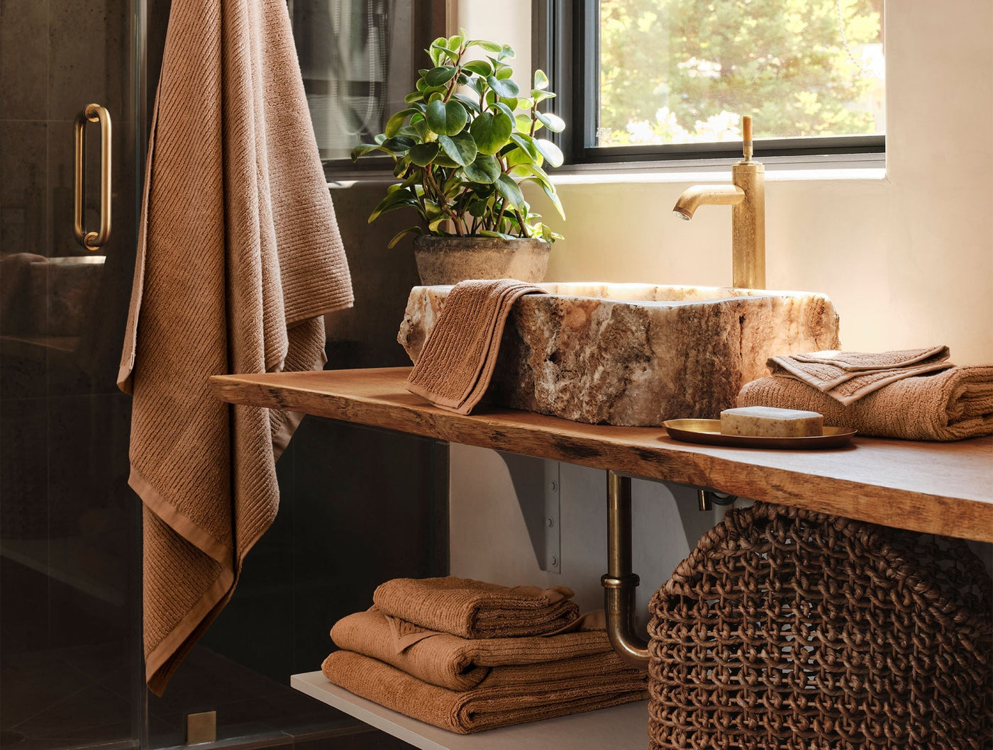 Coyuchi Temescal Ribbed towels styled in warm caramel on rustic wood vanity.