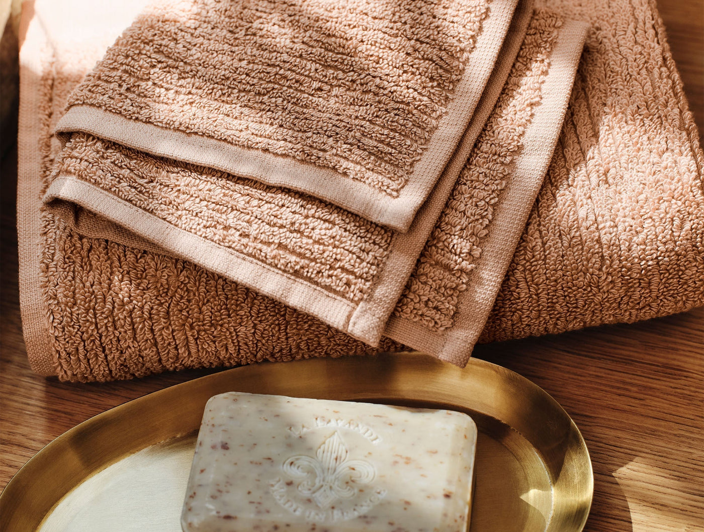 Close-up of folded terracotta Coyuchi Temescal towels with ribbed border detail, styled with soap.