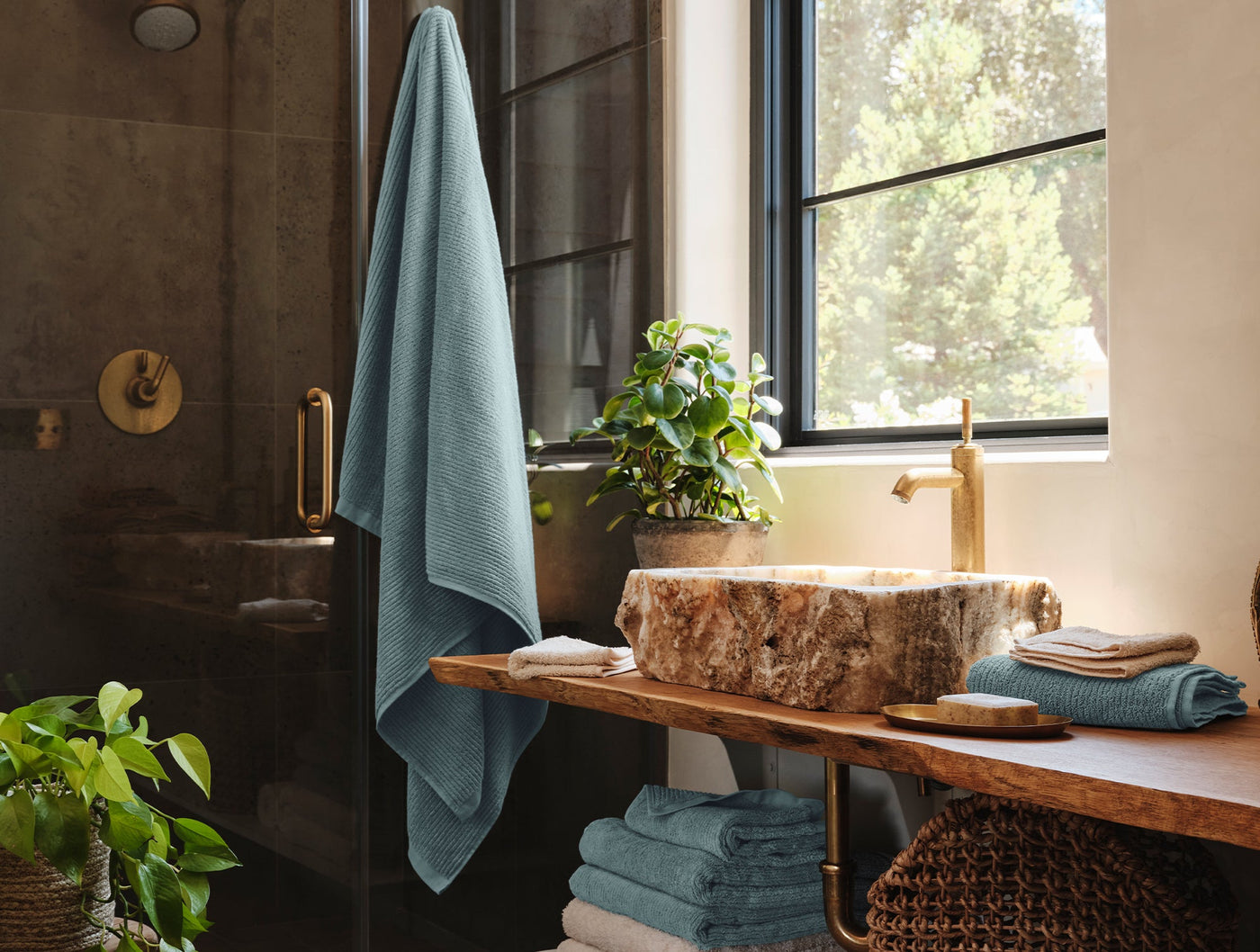 Coyuchi Temescal Ribbed towels in slate blue styled in a moody stone bathroom.