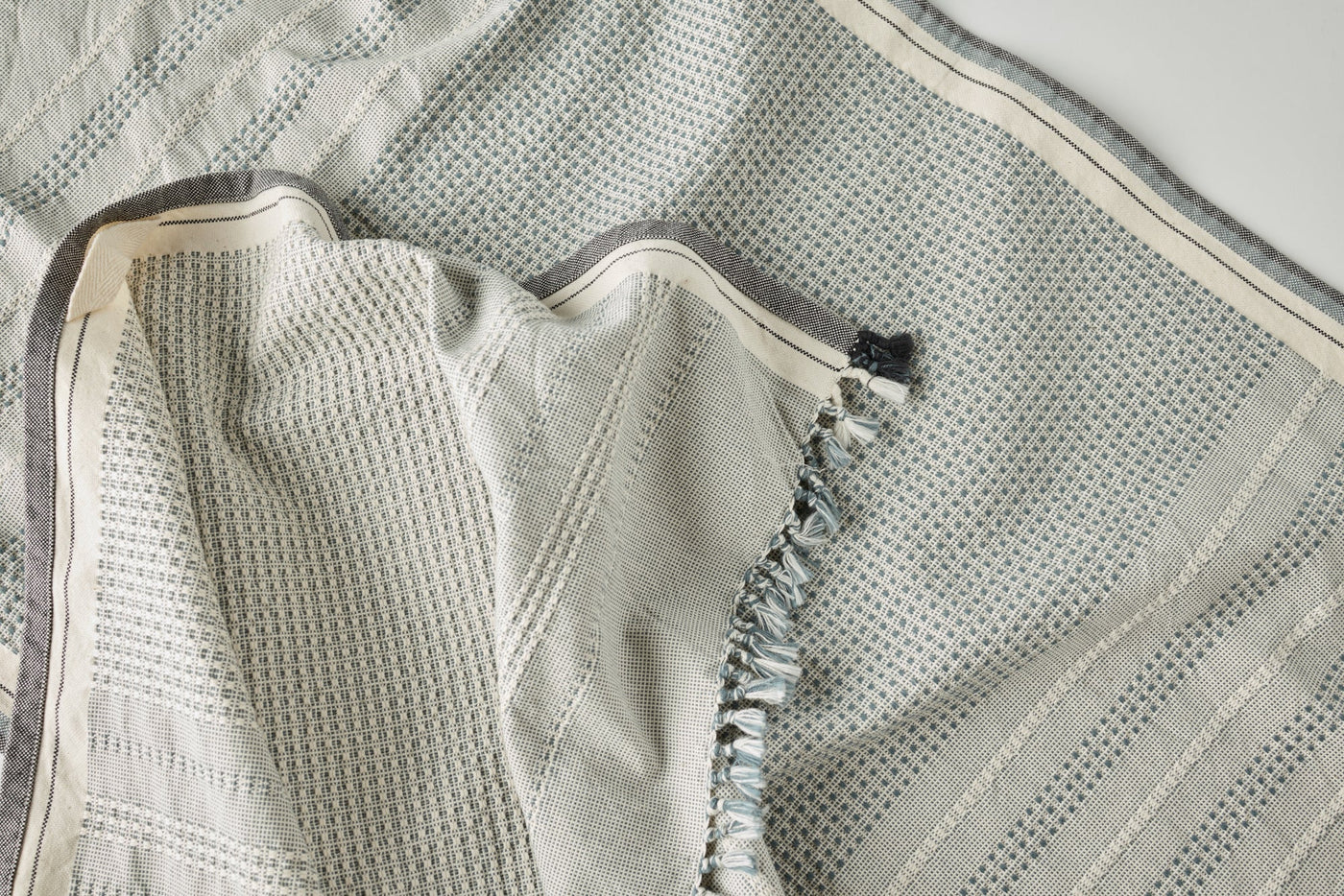 Close-up of Coyuchi Bay hand towel in silver, showing waffle weave texture and fringe edge detail.