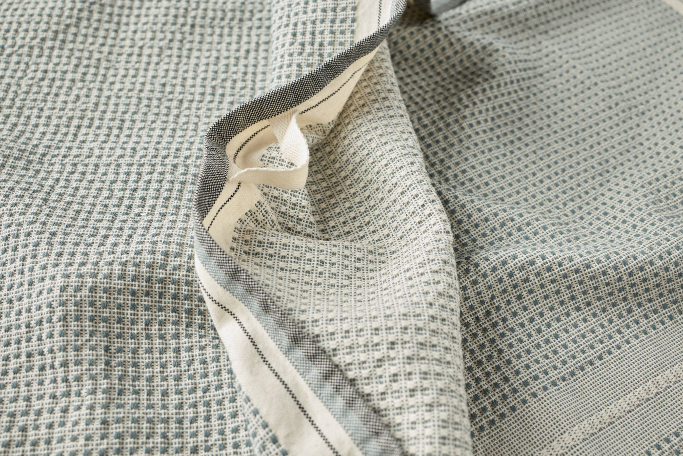 Close-up of Coyuchi Bay hand towel in sage, showing waffle weave texture and contrast trim detail.