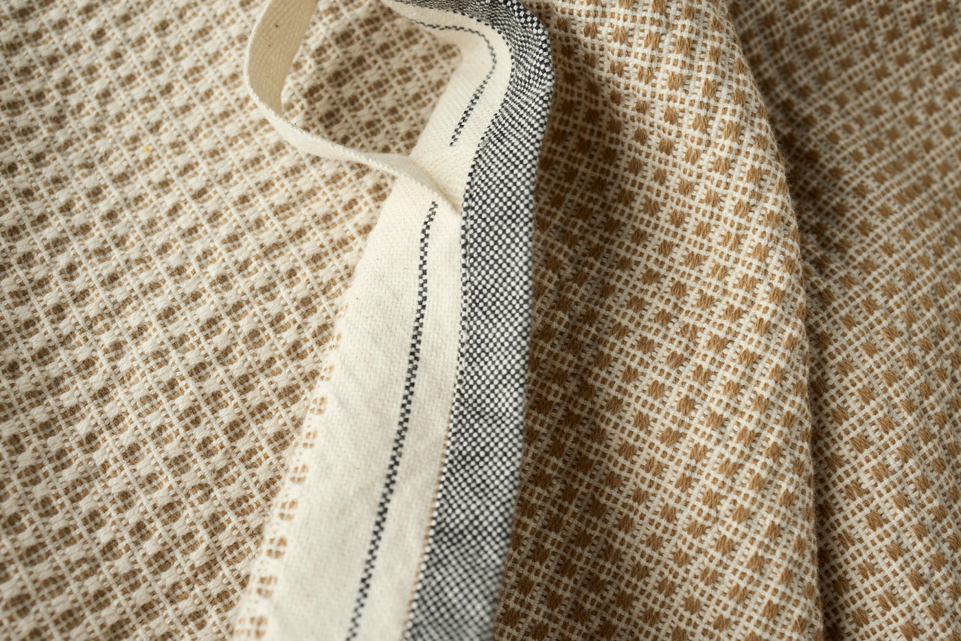 Close-up of Coyuchi Bay hand towel hem, showing camel woven pattern and ivory stripe border detail.