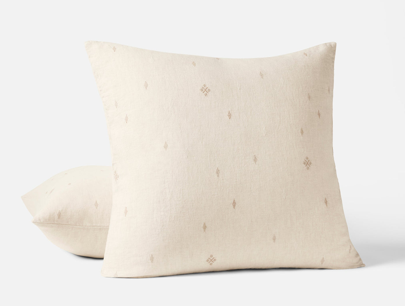 Close-up of two ivory Coyuchi Cambria linen shams with scattered diamond embroidery motifs.