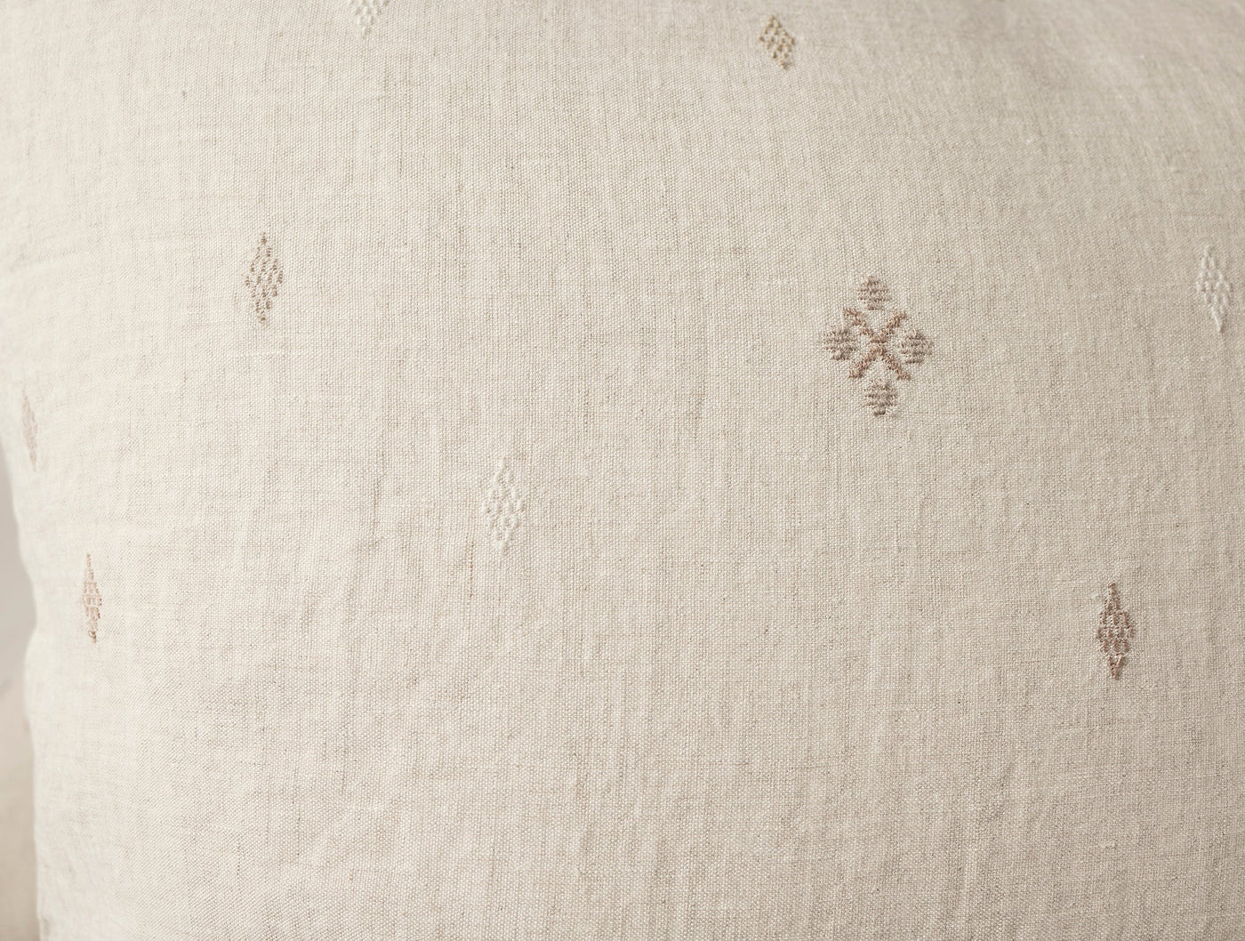 Close-up of ivory linen sham with subtle taupe diamond embroidery motifs.