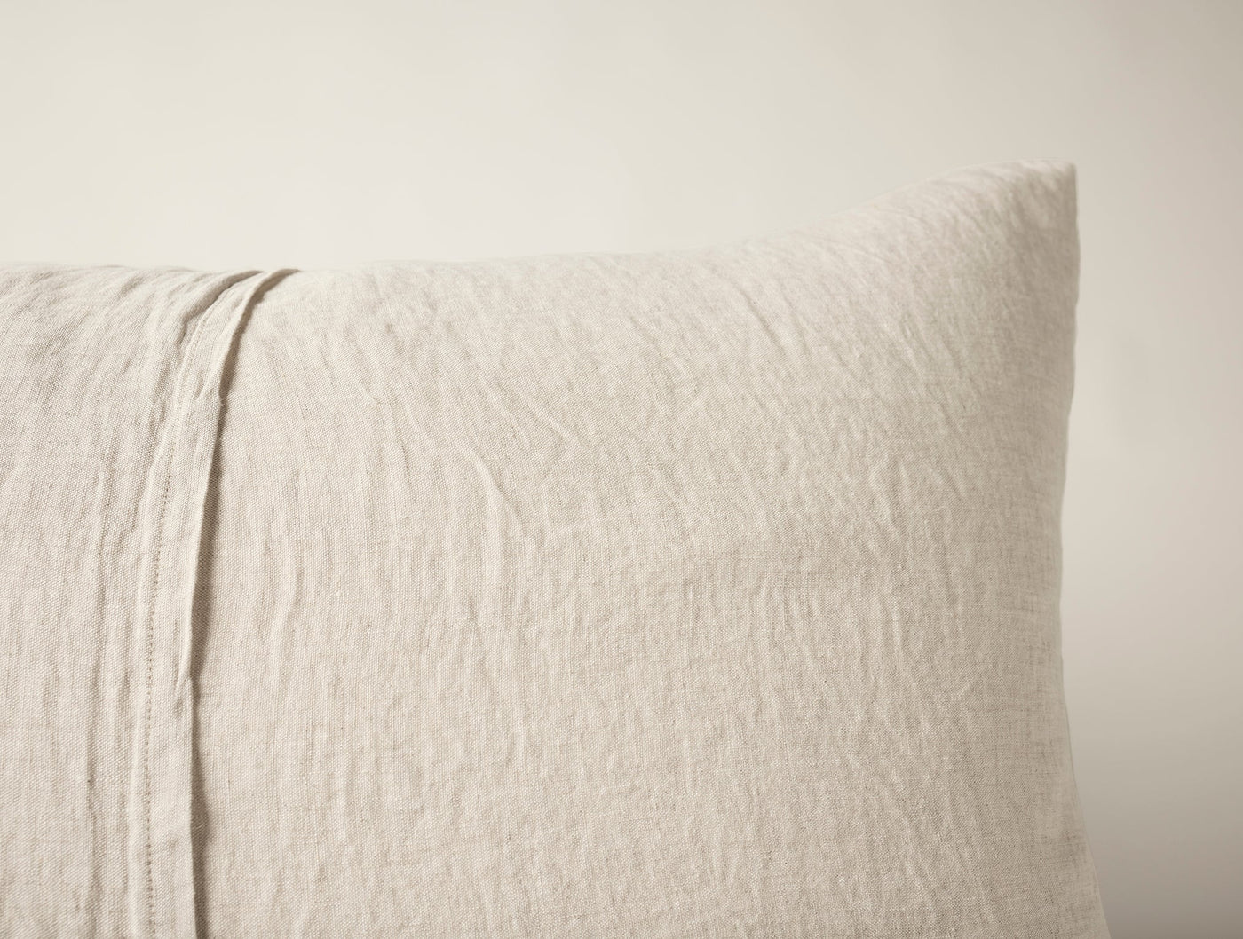 Close-up of natural linen pillow sham corner showing relaxed texture and subtle seam detail.