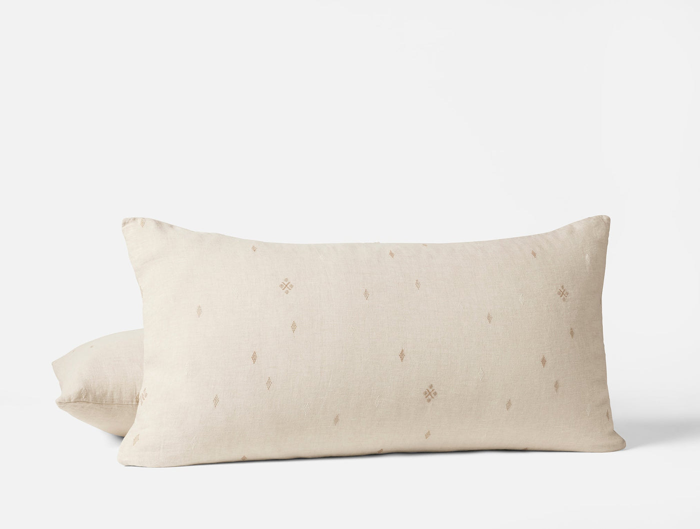 Close-up of Coyuchi Cambria ivory linen pillow shams showing diamond embroidery motifs.