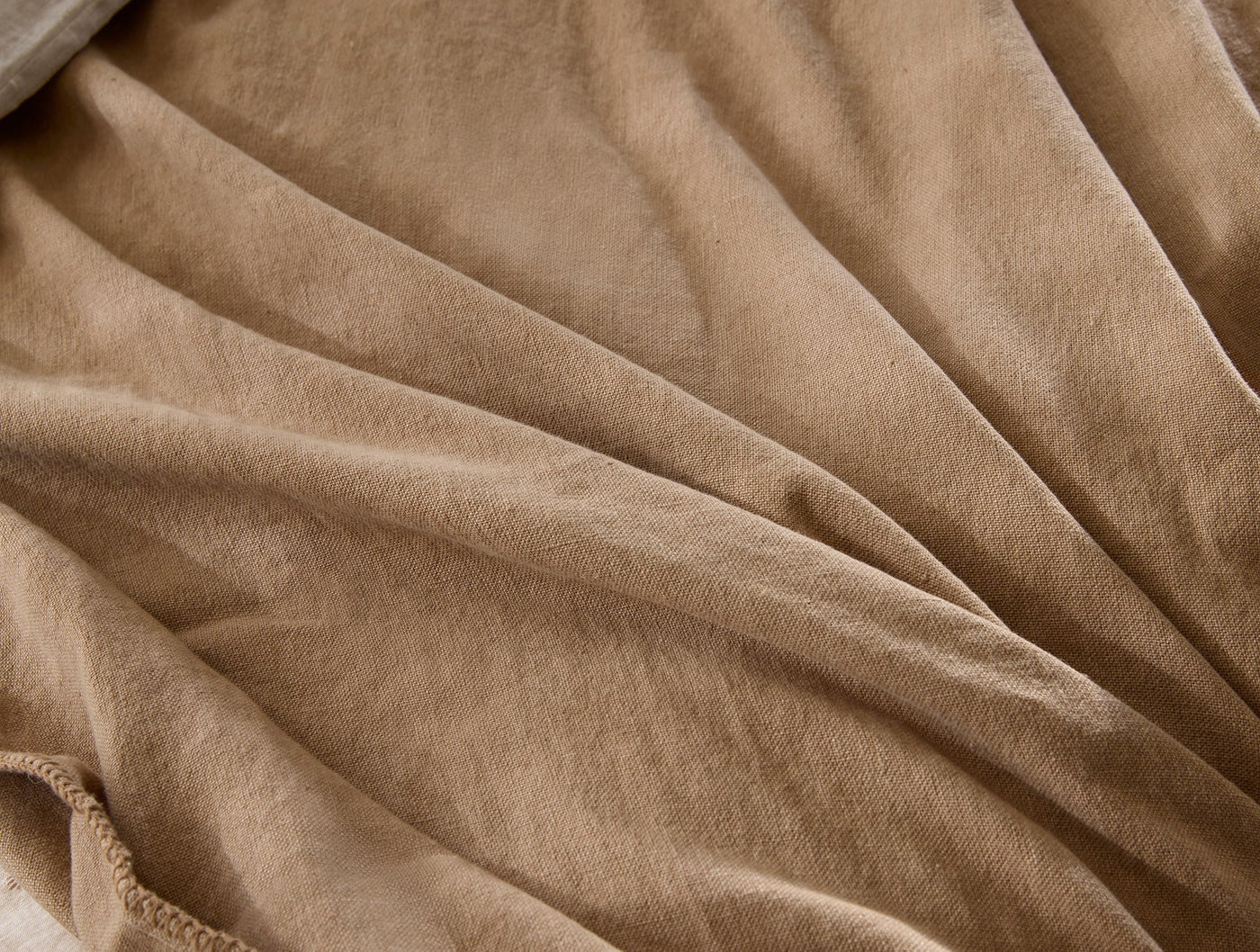 Camel-toned linen throw fabric, close-up showing soft drape and subtle texture.