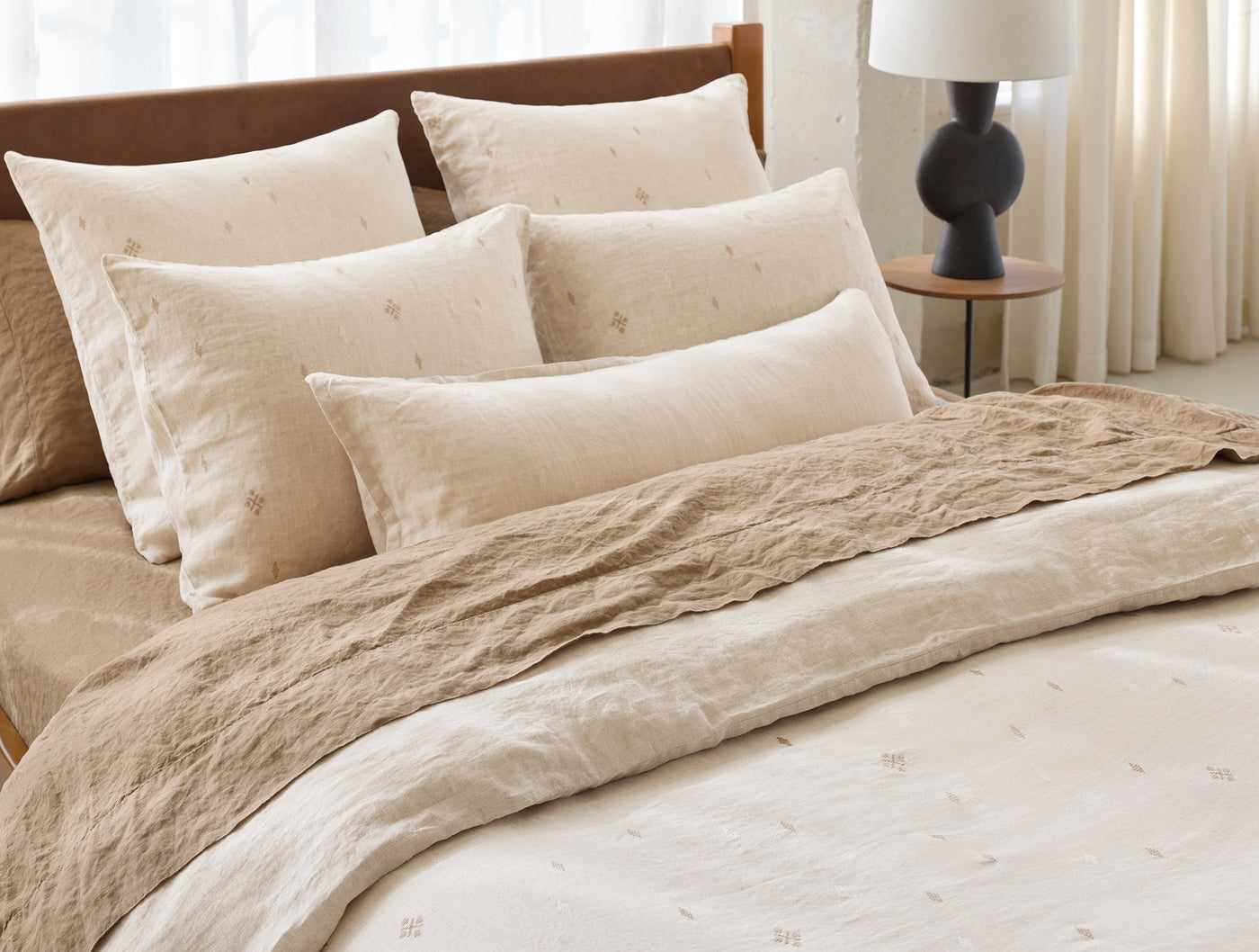 Coyuchi Cambria duvet cover styled on bed with layered ivory and sand linen bedding.
