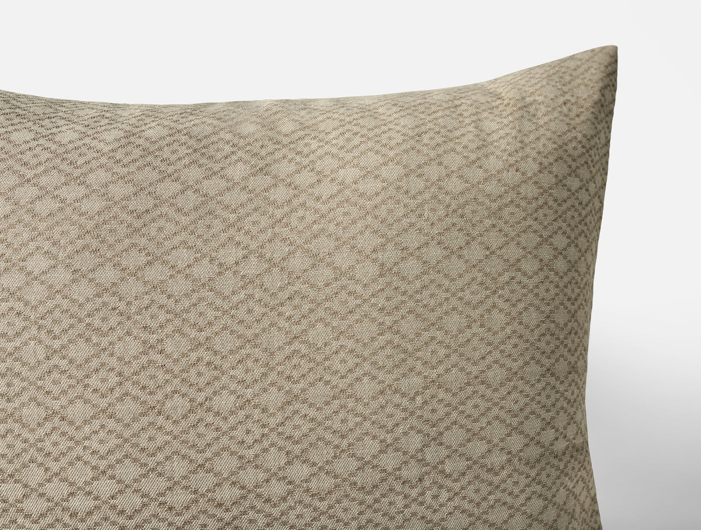 Close-up of Coyuchi Capitola sham corner in warm tan with woven diamond lattice pattern.