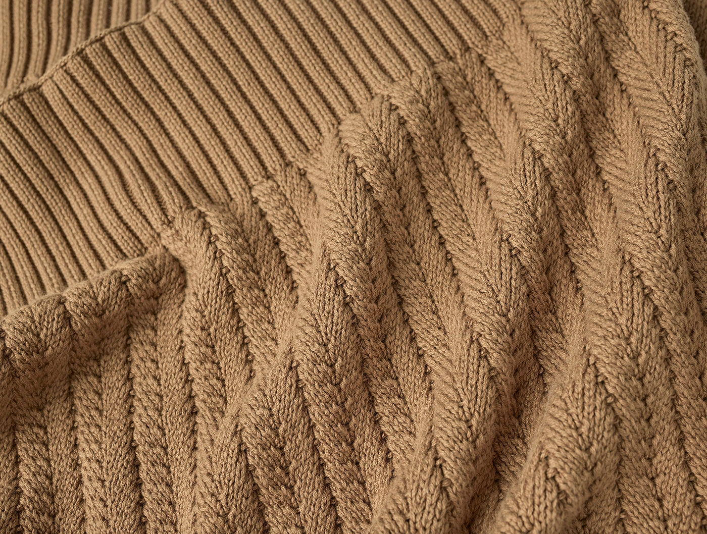Close-up of Coyuchi Casa Loma Knit Throw in camel, showing cable-knit texture and ribbed hem.