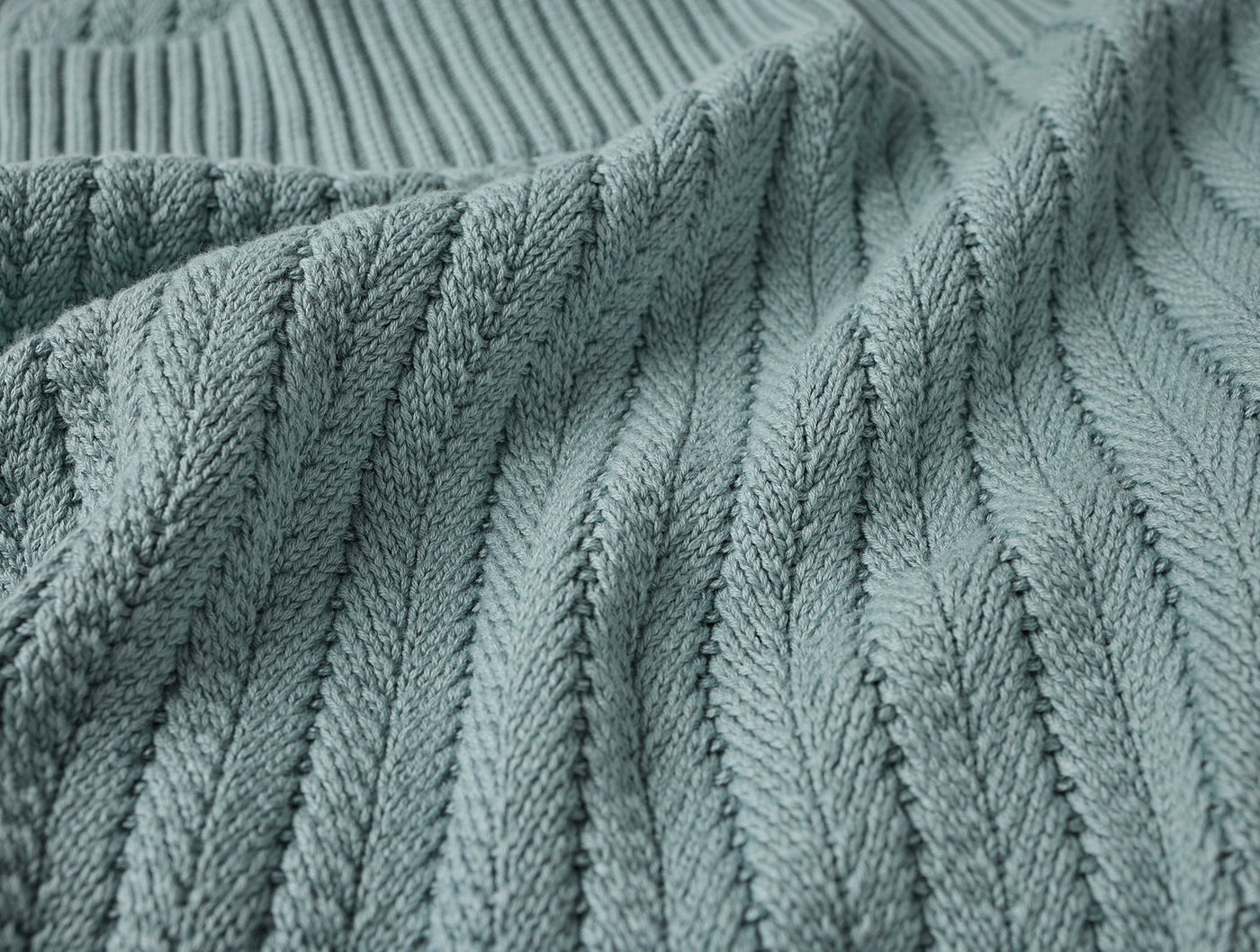 Close-up of sage green cable-knit weave texture on Coyuchi Casa Loma throw.