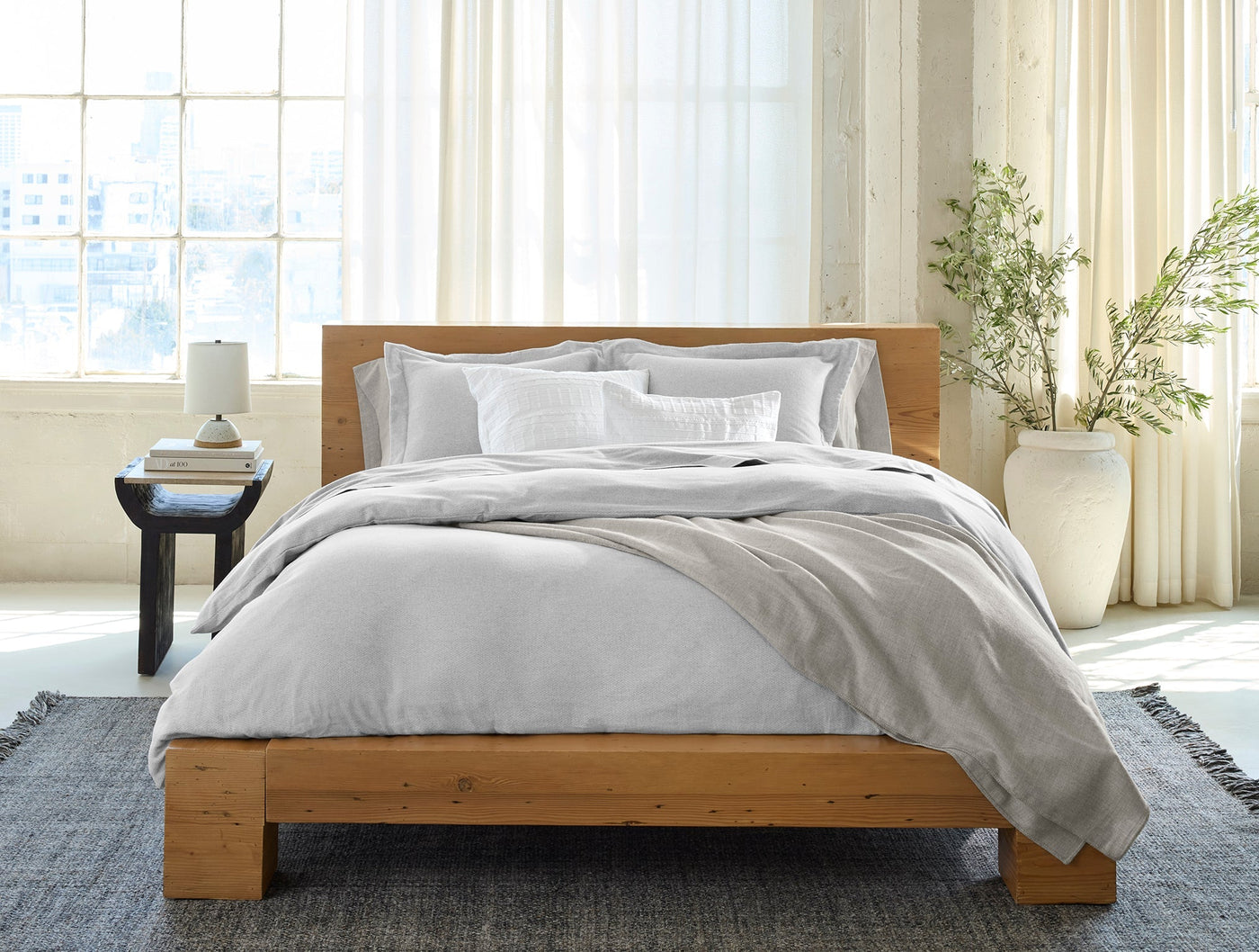 Coyuchi Cloud Brushed Flannel duvet cover in light grey on a natural wood bed.