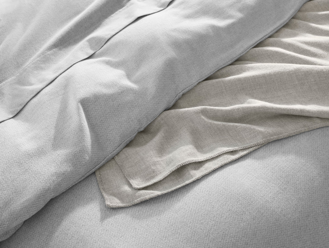 Close-up of Coyuchi Cloud Brushed Flannel sham edge, silver and natural linen tones layered.