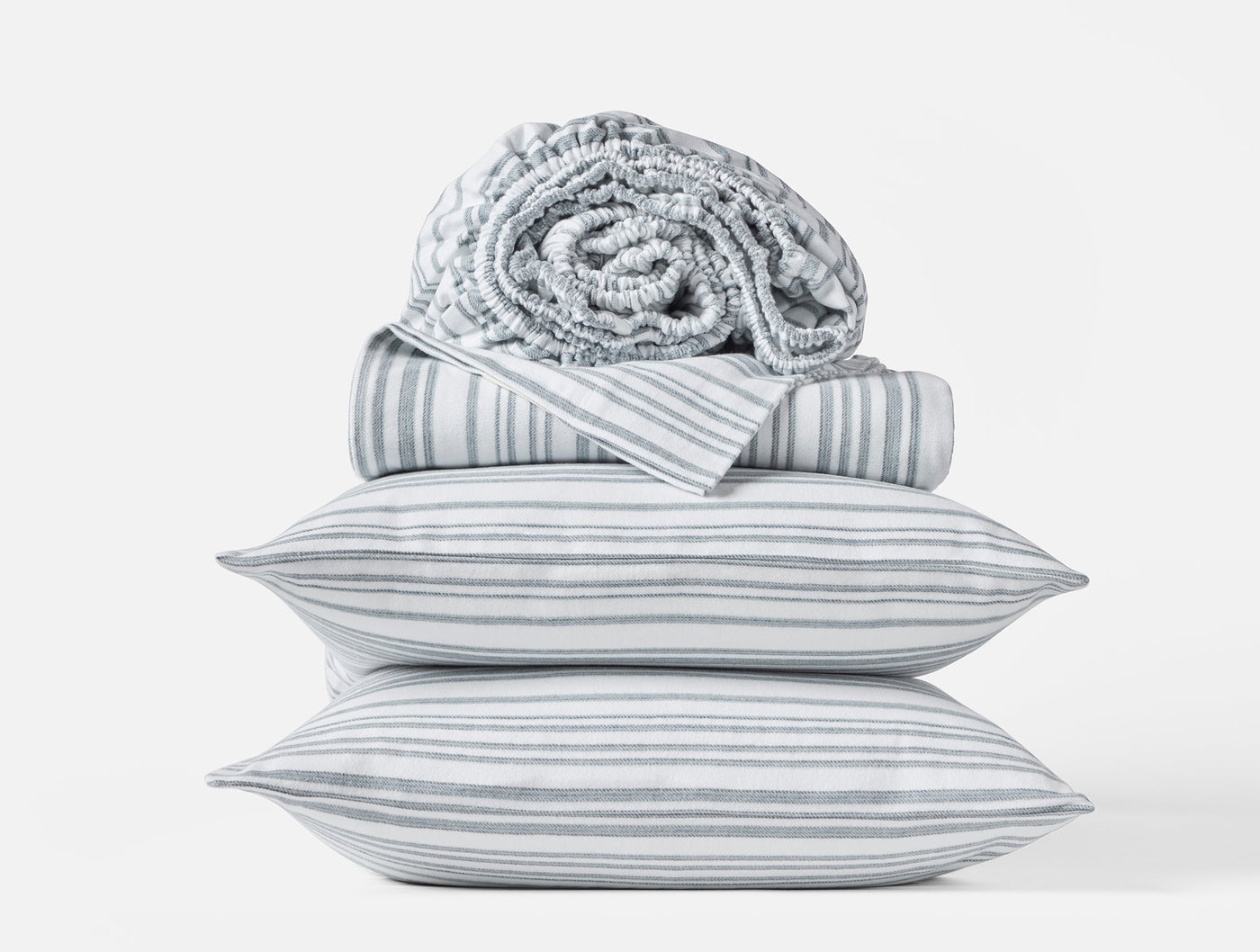 Close-up stack of Coyuchi Cloud Brushed Flannel sheet set in grey multi-stripe pattern.