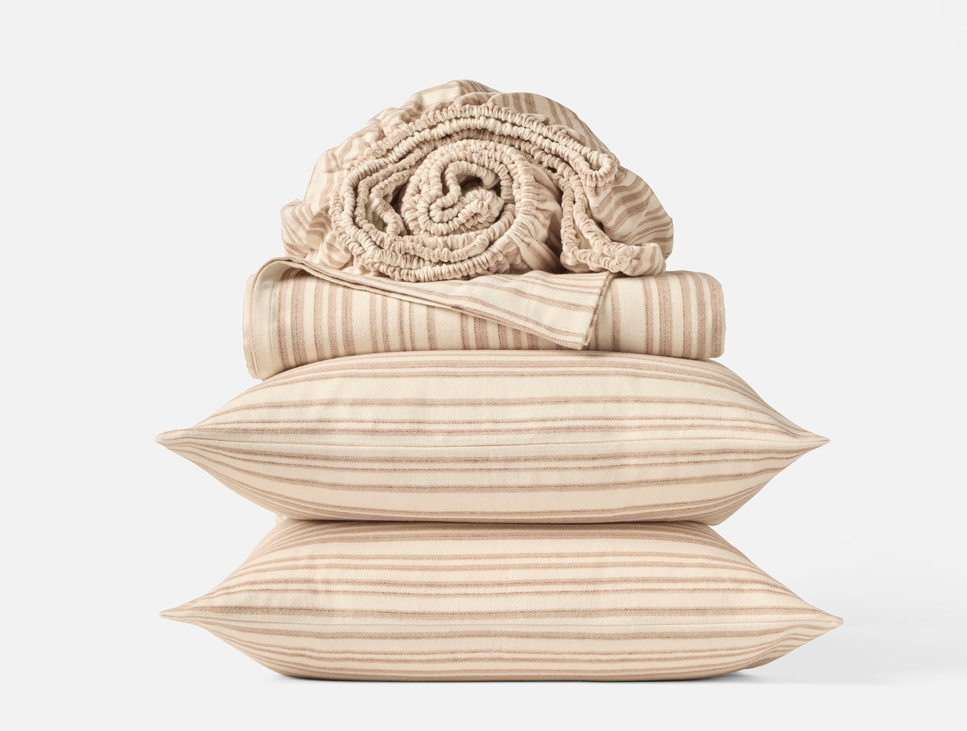 Close-up of stacked Coyuchi flannel pillowcases and rolled blanket in warm stripe pattern.