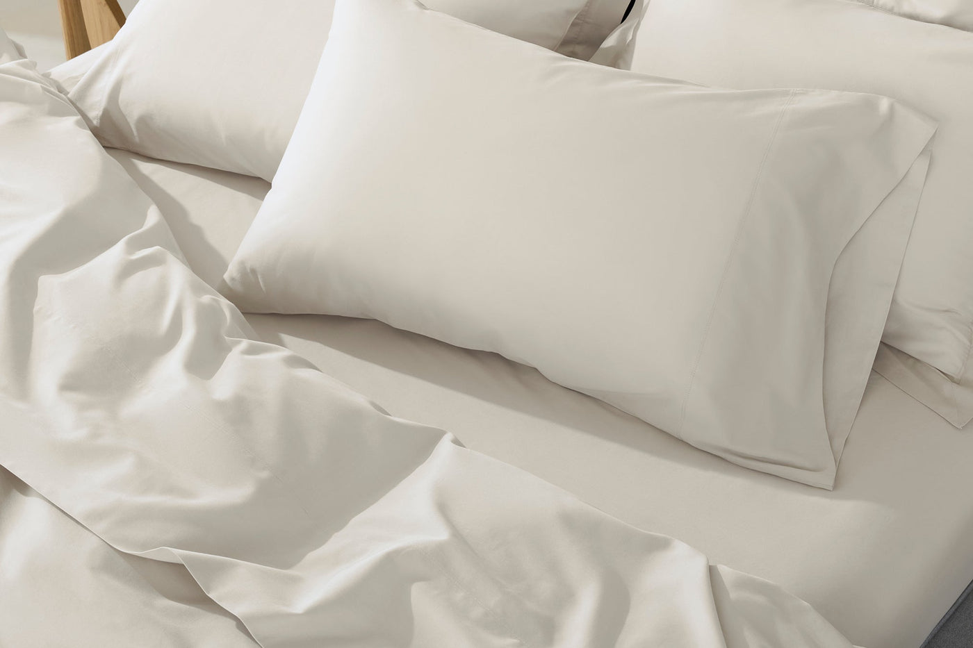 Close-up of ivory Coyuchi Cloud Soft Sateen pillowcases on a softly rumpled bed.