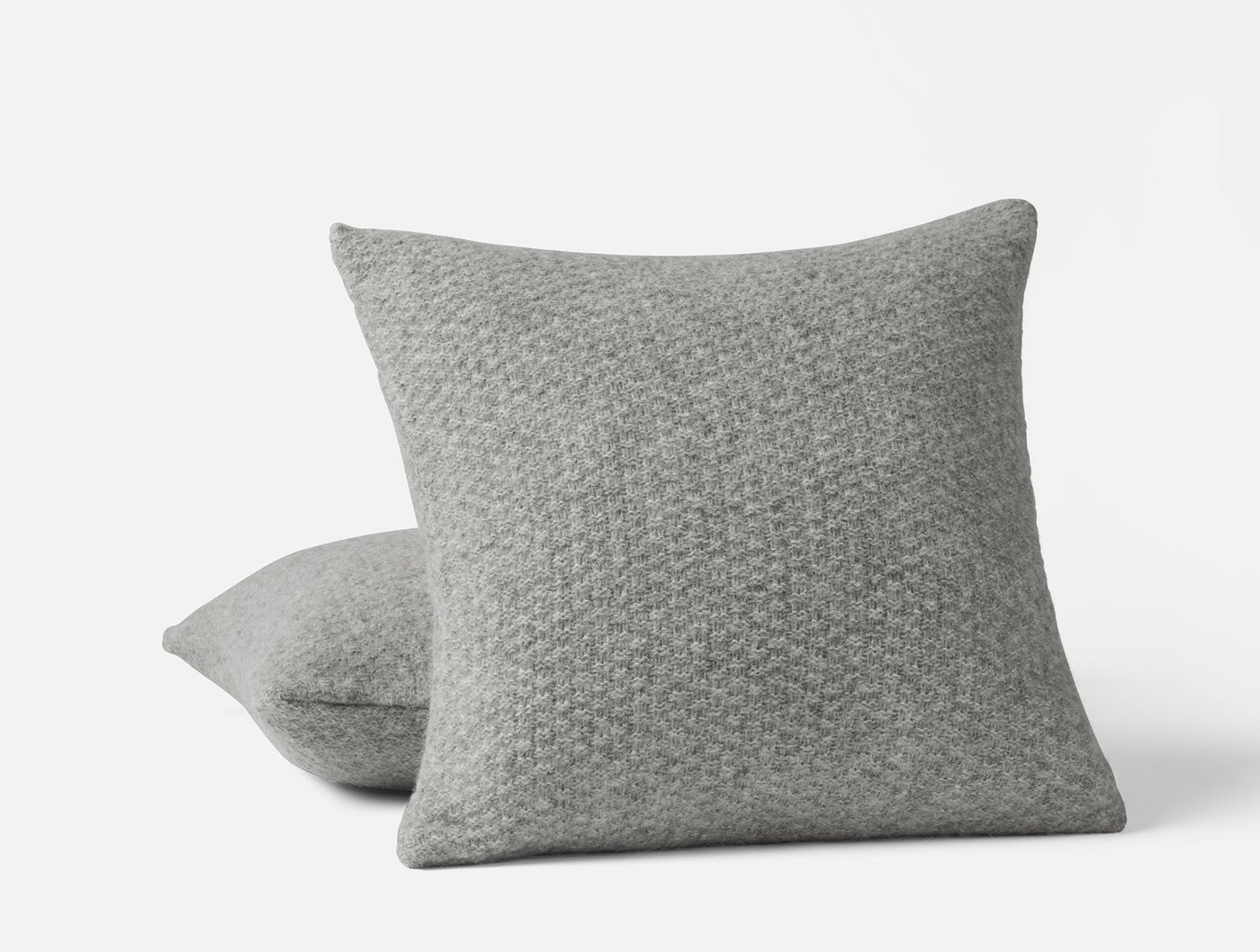 Close-up of two Coyuchi Cordillera pillows in grey alpaca-cotton knit with textured weave pattern.
