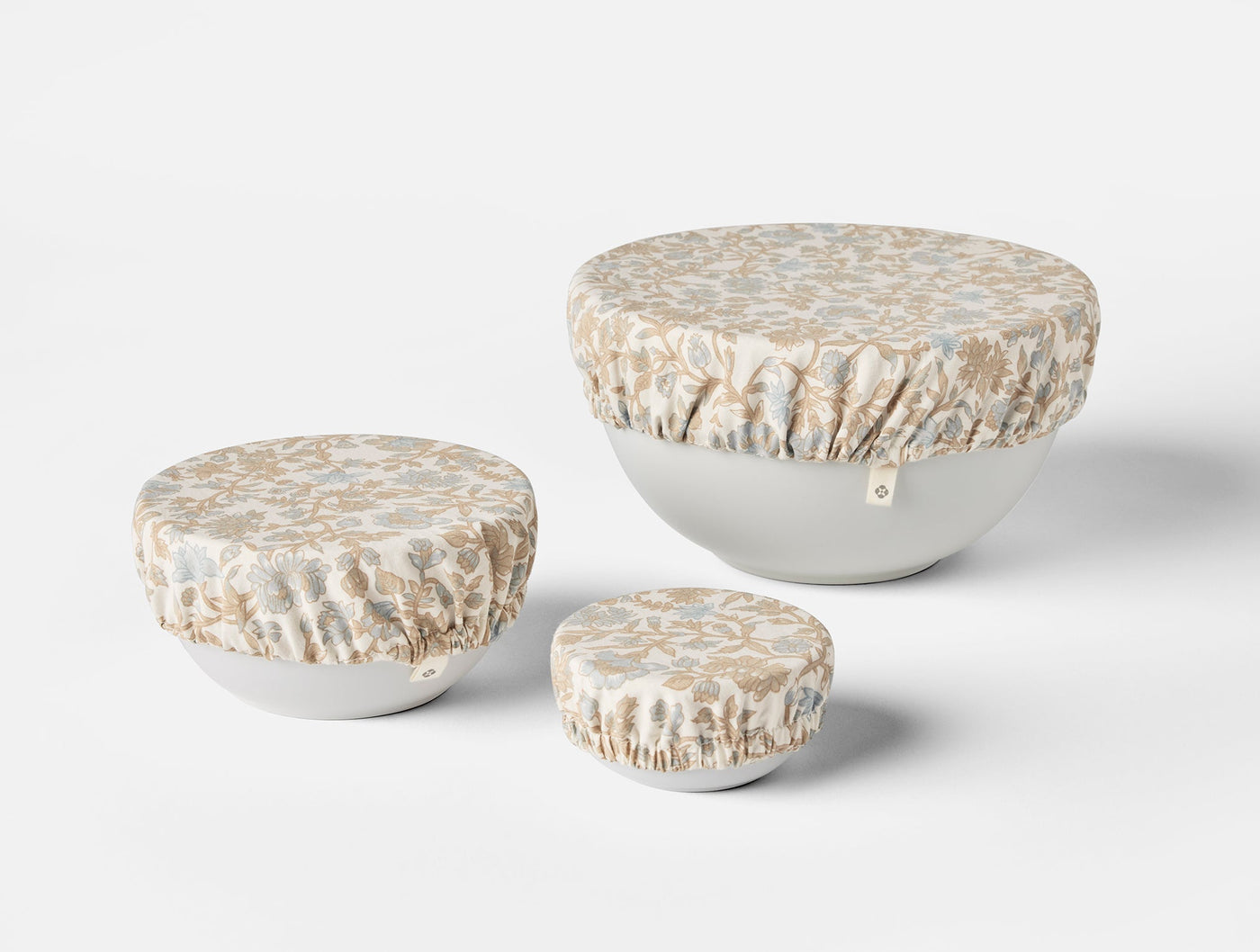 Coyuchi Conserve bowl cover set in three sizes, ivory floral print fabric stretched over white bowls.