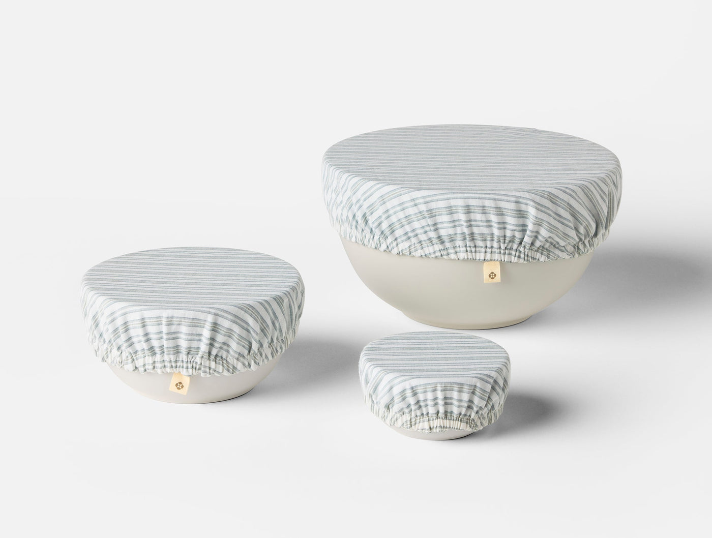 Three Coyuchi Conserve bowl covers in blue stripe, shown on small, medium, and large bowls.
