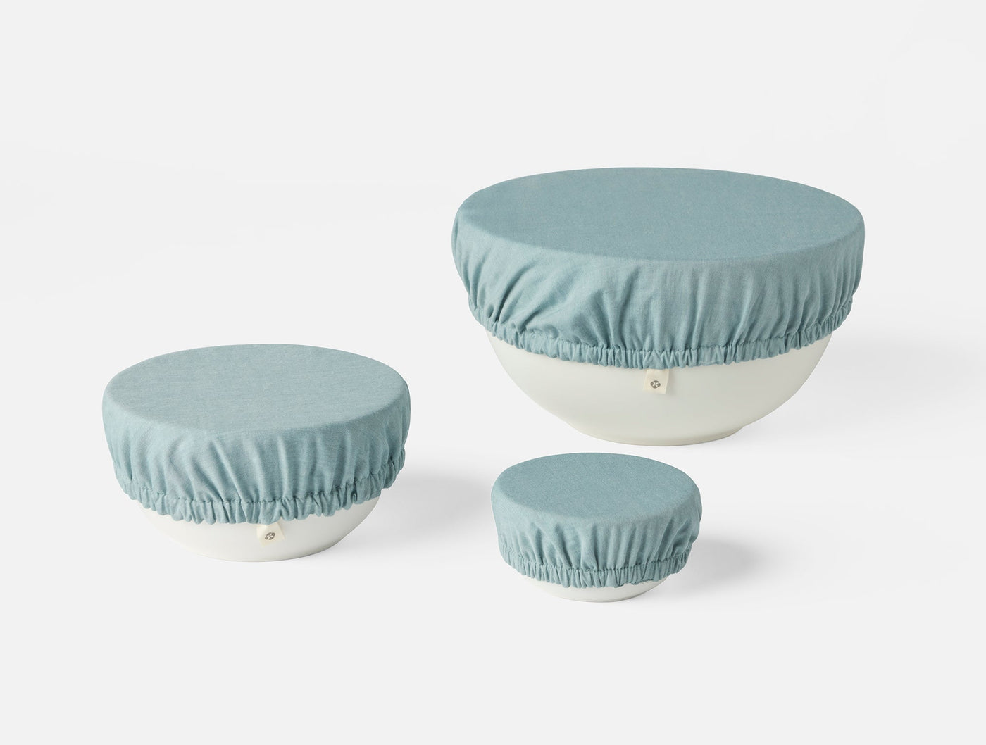Three Coyuchi Conserve bowl covers in dusty blue linen, shown in small, medium, and large sizes.