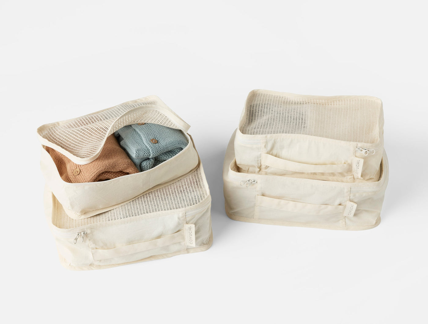 Coyuchi Conserve packing cube set of four in ivory organic cotton with mesh panels.