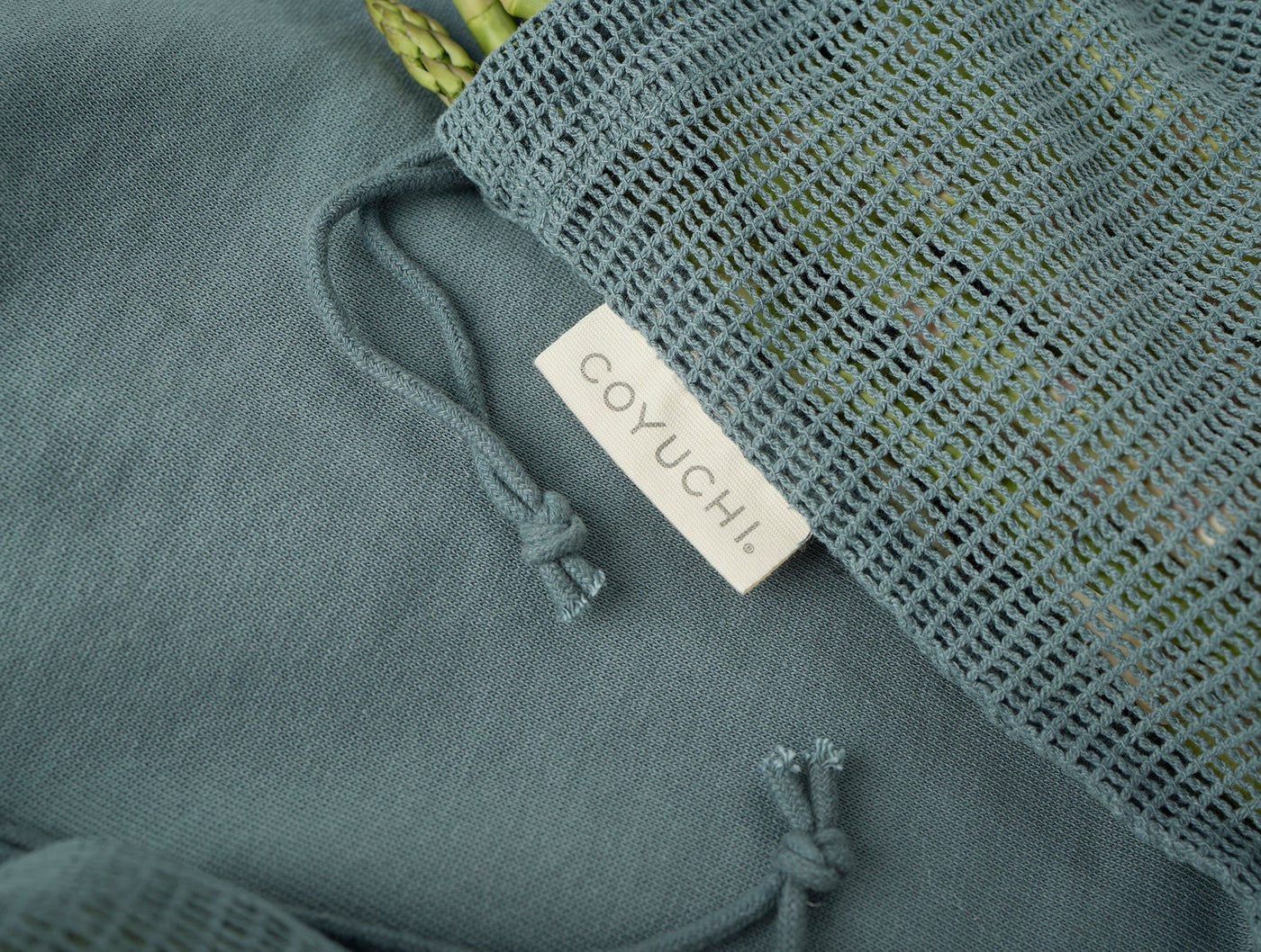 Close-up of Coyuchi slate blue produce bag with woven net panel and knotted ties.