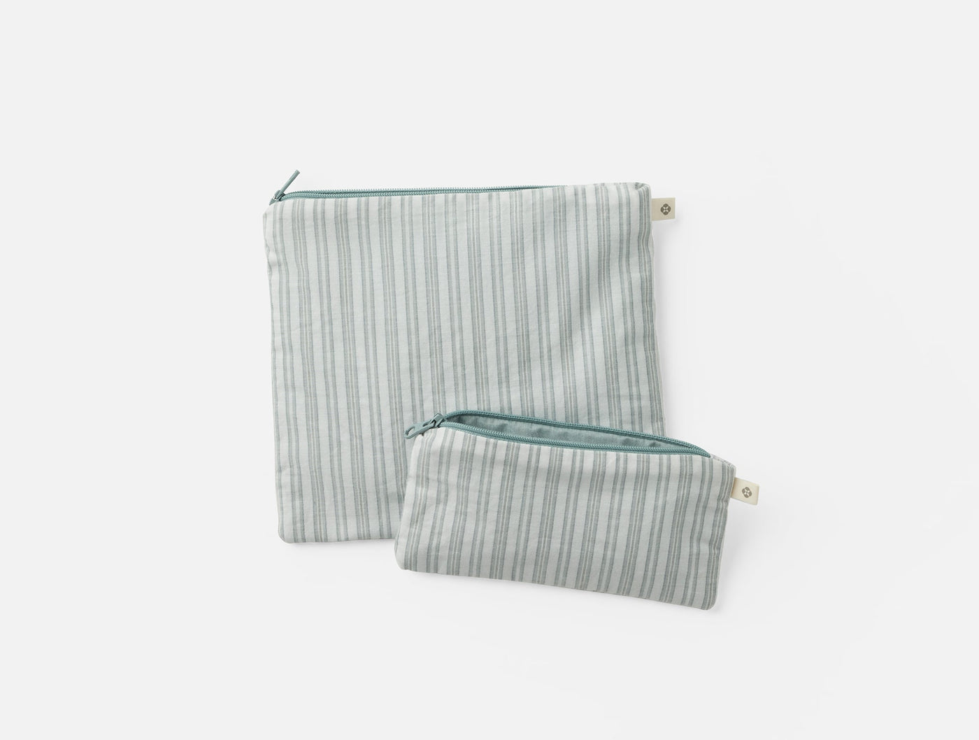 Close-up of two Coyuchi striped linen zip pouches in sage, large and small sizes.