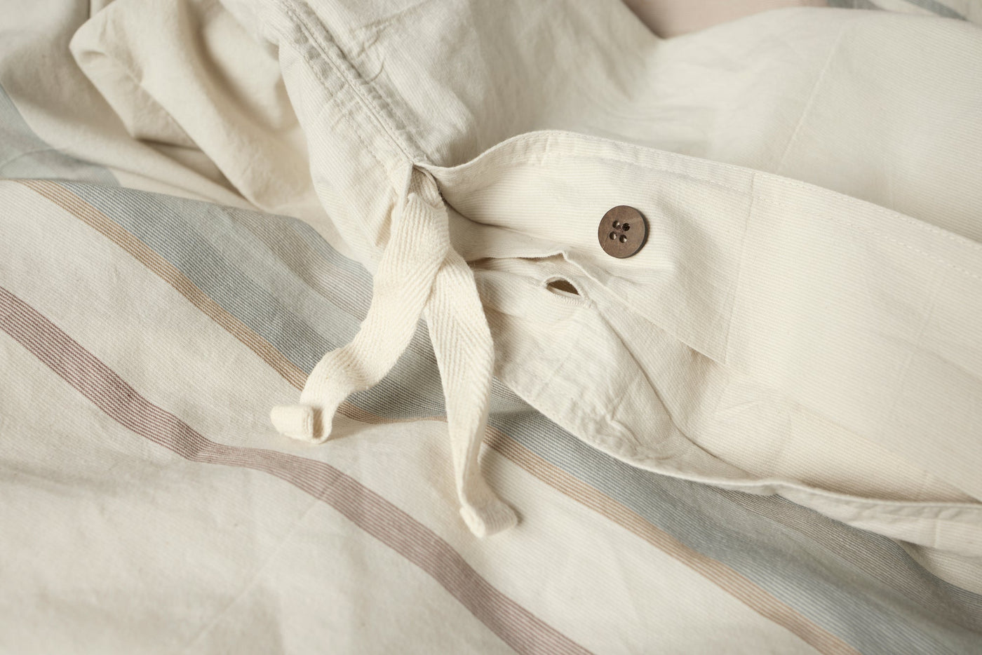 Close-up of Coyuchi Crestridge duvet cover closure with wooden button and fabric ties.