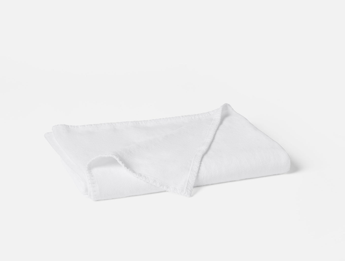 Coyuchi Helena Linen throw in white, folded flat showing fringe edge detail.