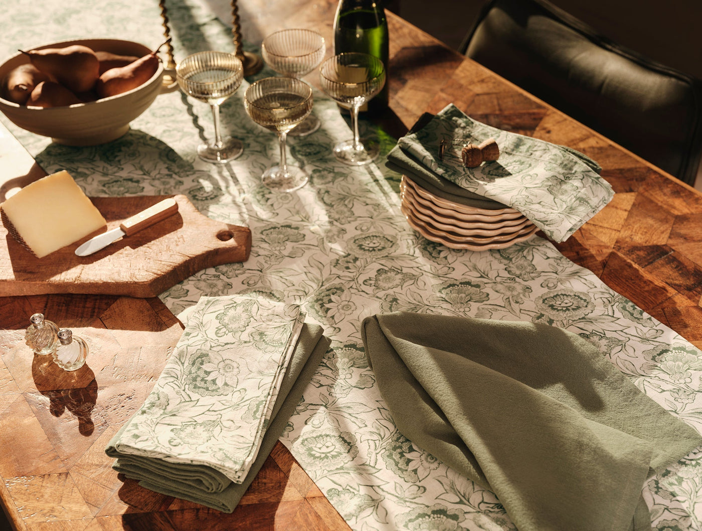 Coyuchi Balboa Print table runner styled on wood table with sage napkins and cheeseboards.