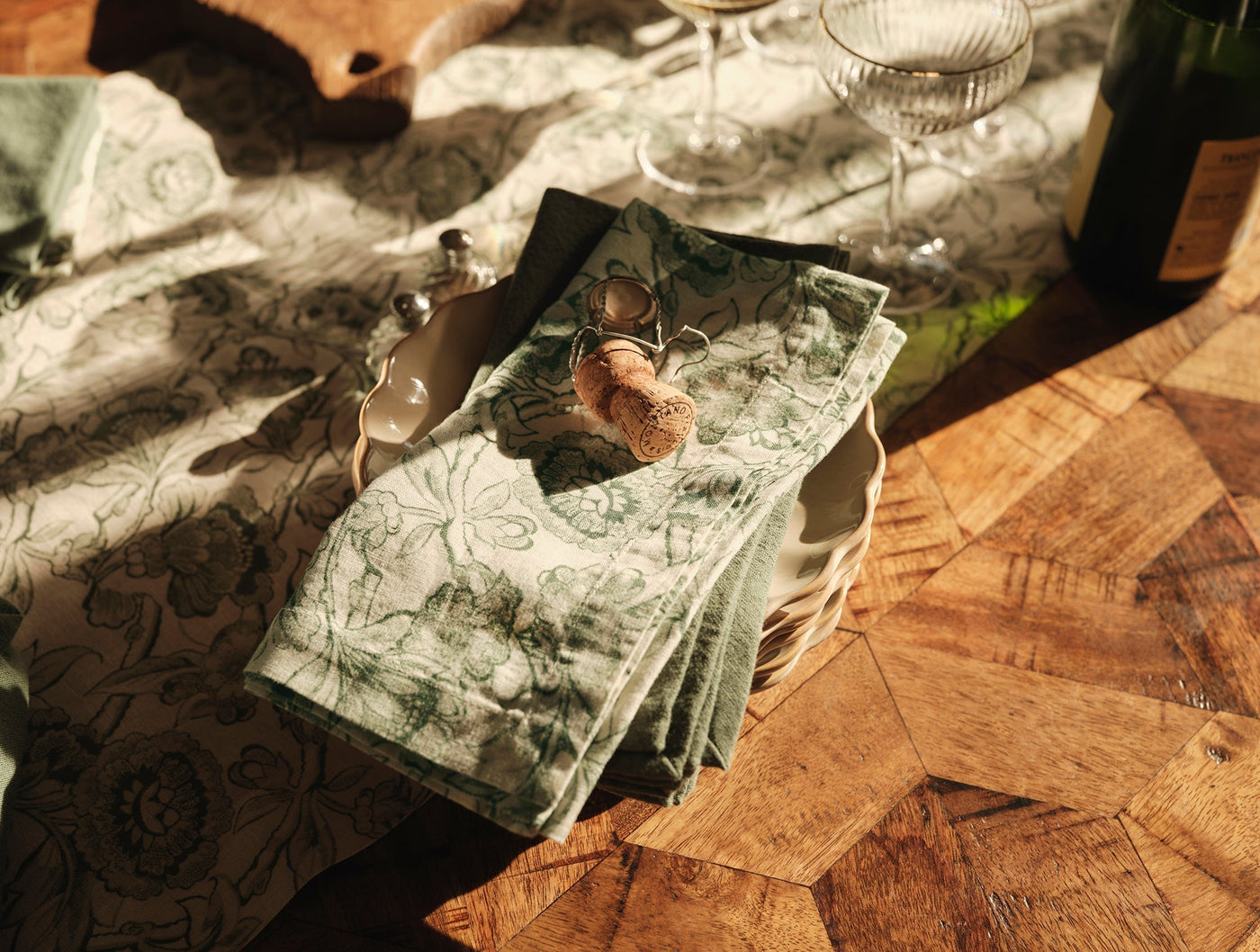 Overhead view of folded Balboa Print runner in sage green floral, styled on a wooden table.