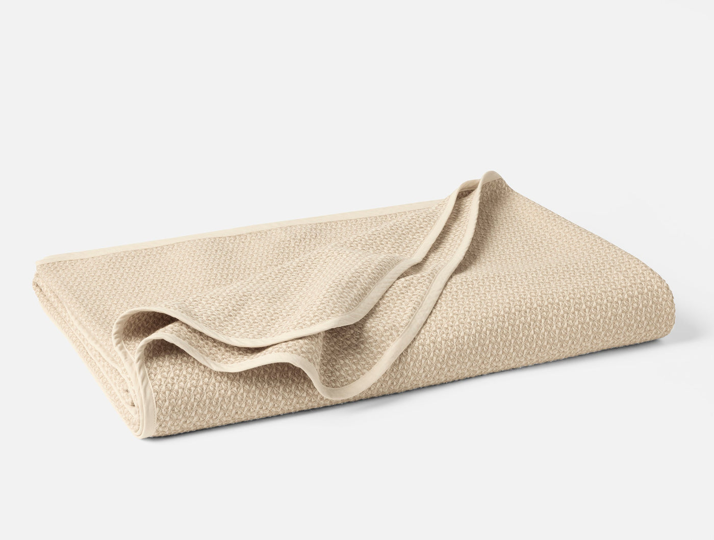 Folded ivory Coyuchi blanket showing honeycomb weave texture detail.