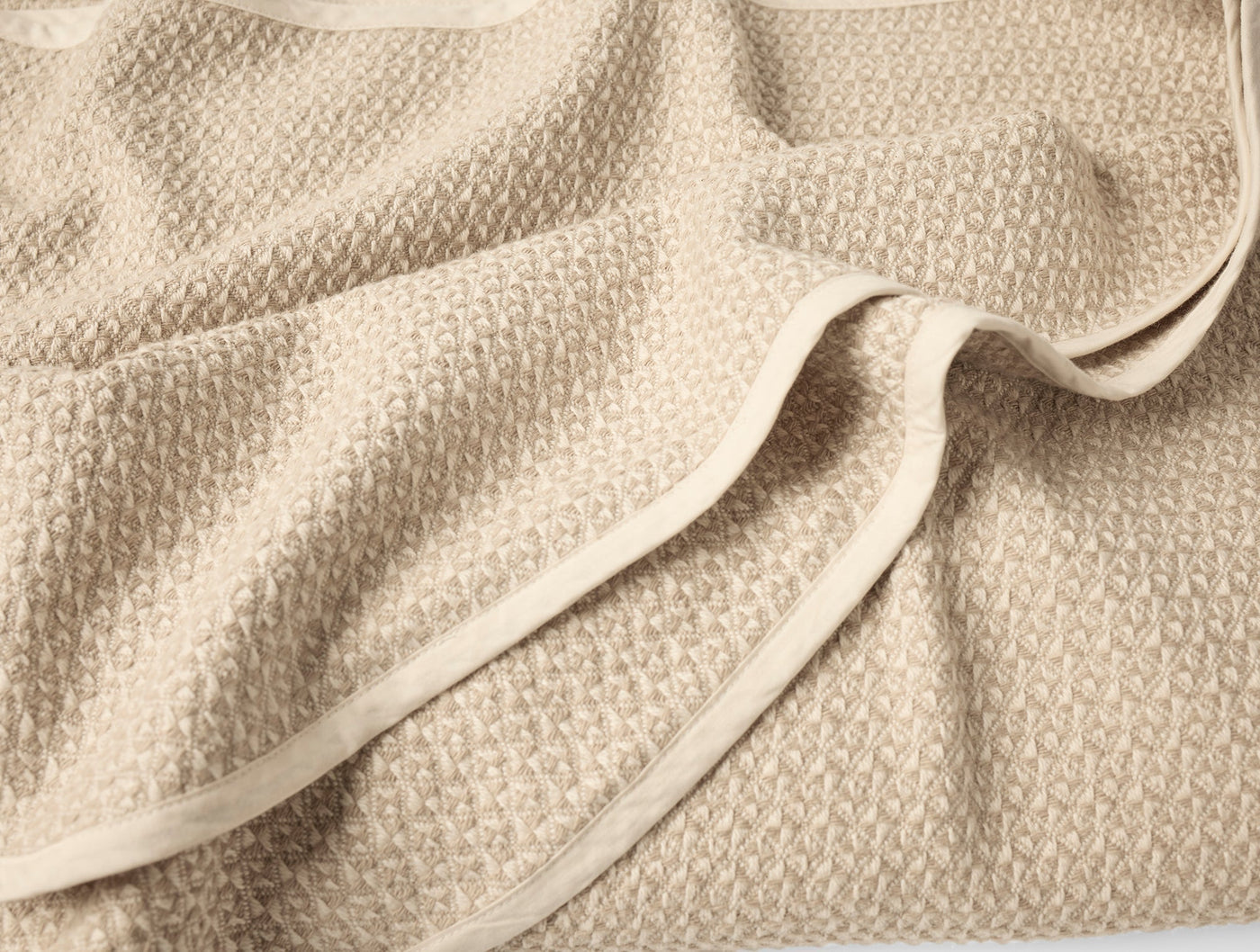 Close-up of Coyuchi Honeycomb blanket hem and textured weave in warm sand.