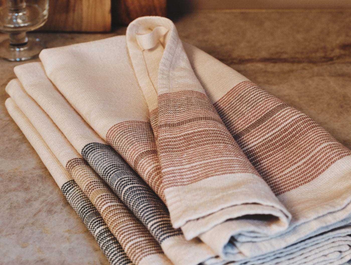 Stacked Coyuchi Miraloma kitchen towels in ivory with woven stripe details in natural and slate.