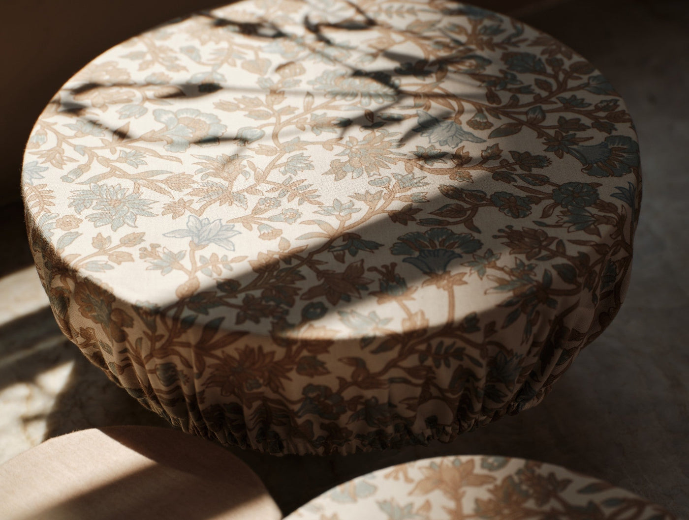 Floral block-print bowl covers in taupe and sage, elasticized edges, dappled sunlight.