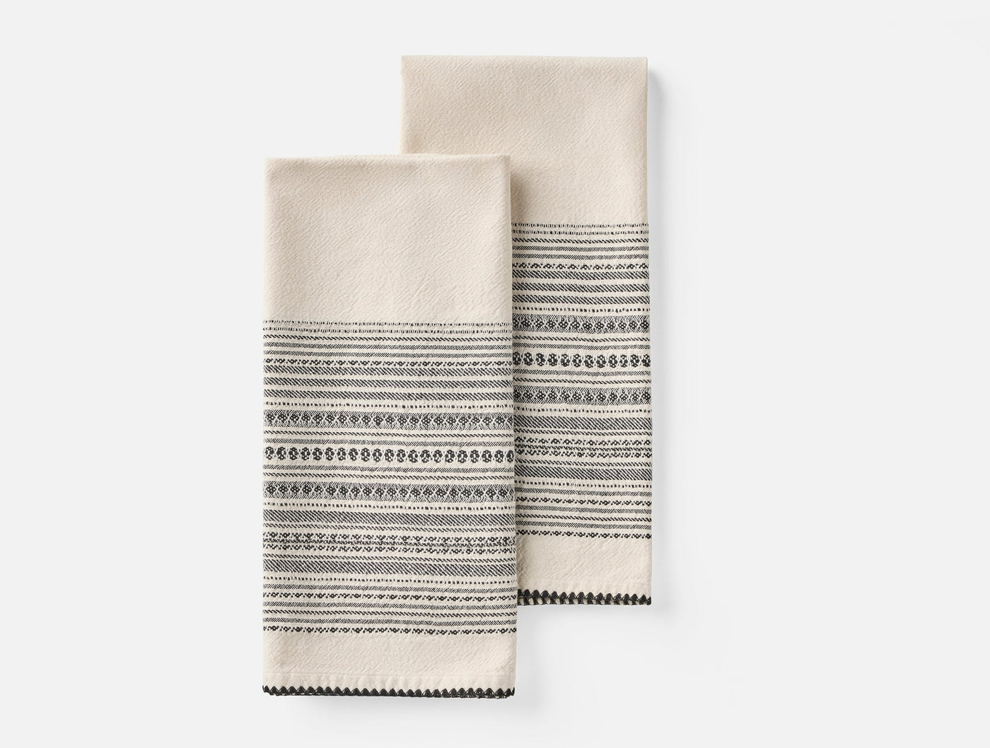 Close-up of two folded Coyuchi Oak hand towels in ivory with dark charcoal woven stripe border detail.