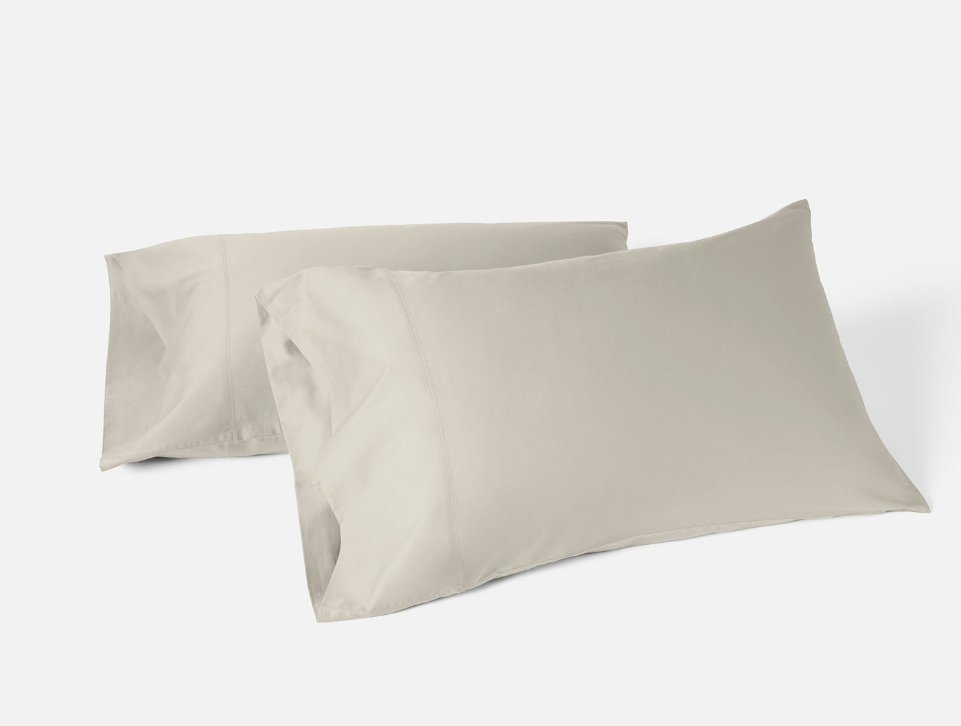 Two Coyuchi Cloud Soft Sateen pillowcases in stone, overlapping on white background.